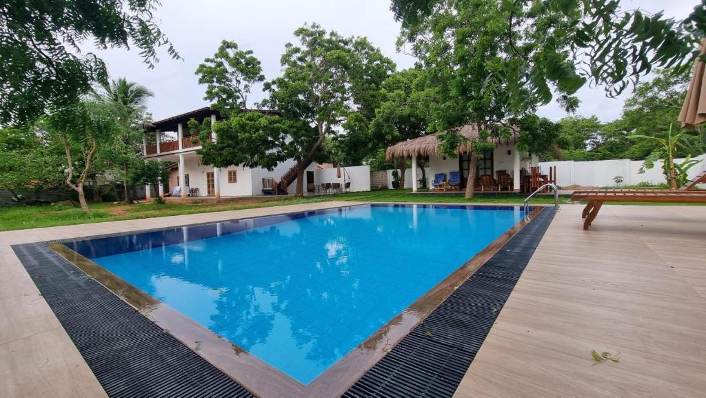 a swimming pool with a bench in front of a house at Kirinda Heaven - Yala in Kirinda