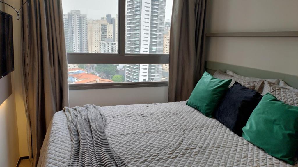 a bedroom with a bed with green pillows and a window at VN Turiassu II in Sao Paulo