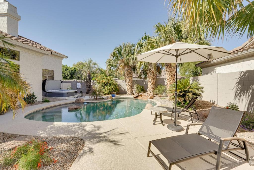a swimming pool with an umbrella and two chairs and a table at Luxe Scottsdale Retreat Pool, Hot Tub and More! in Phoenix