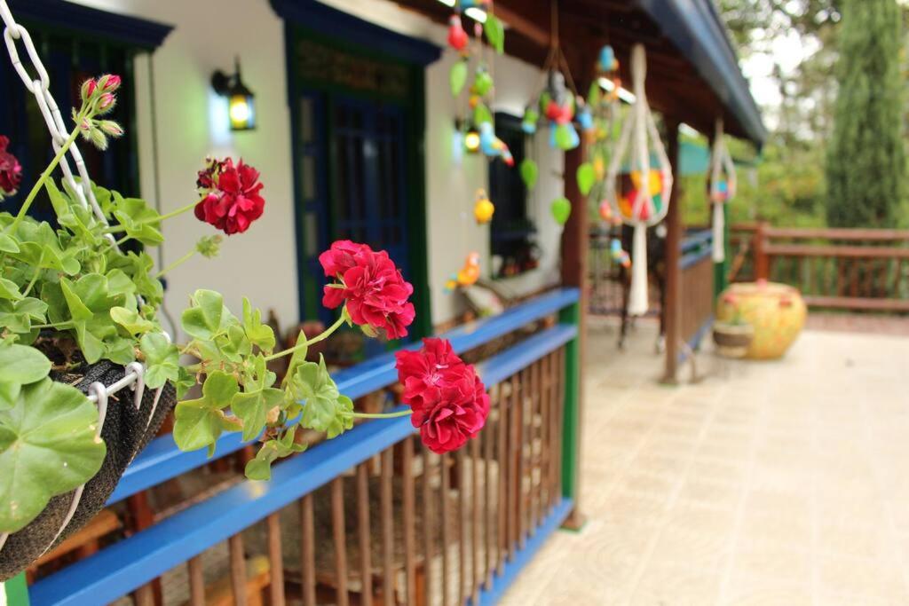 un balcón con flores rojas en una casa en La Juanita Casa Hotel Ecológico, en La Estrella