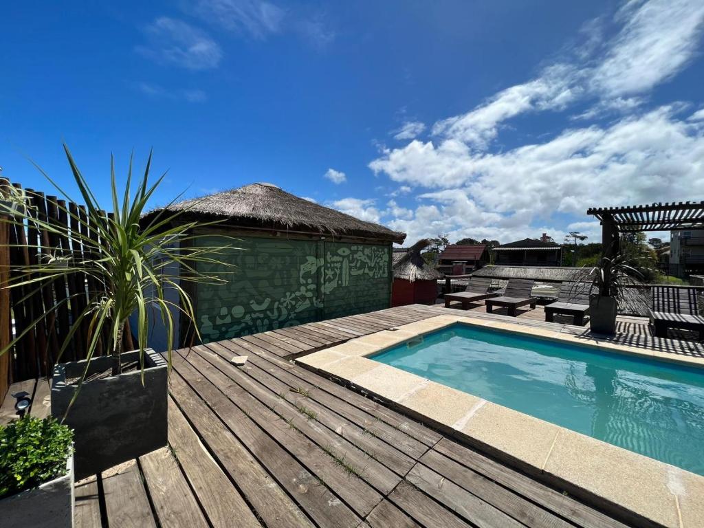 a wooden deck with a swimming pool and a wooden deck at Pueblo Arriba Hostel in Punta Del Diablo