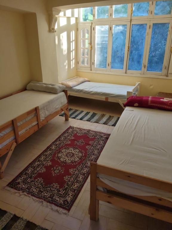 a room with three beds and a rug at Villa Elaraby Mohamed in Aswan