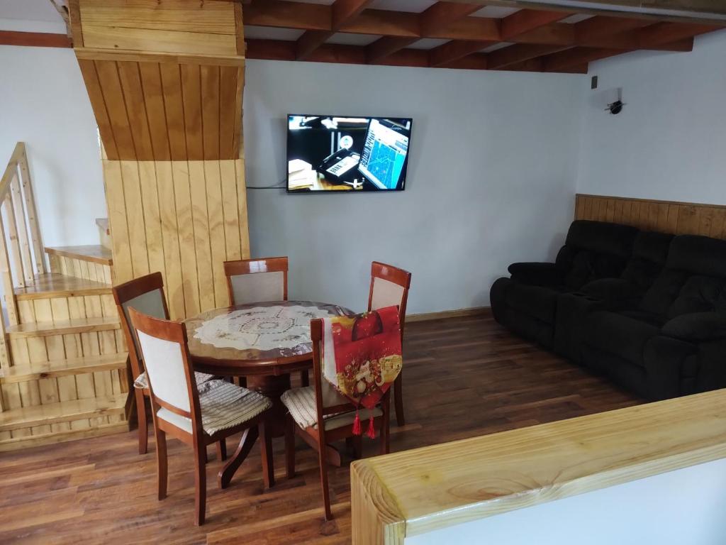 sala de estar con mesa, sillas y sofá en Cabañas Vera, en Punta Arenas