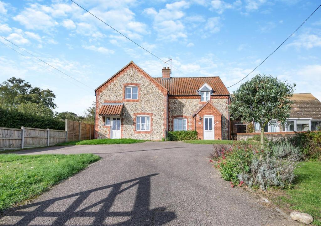 a large brick house with a driveway at Pebble Cottage in Little Walsingham
