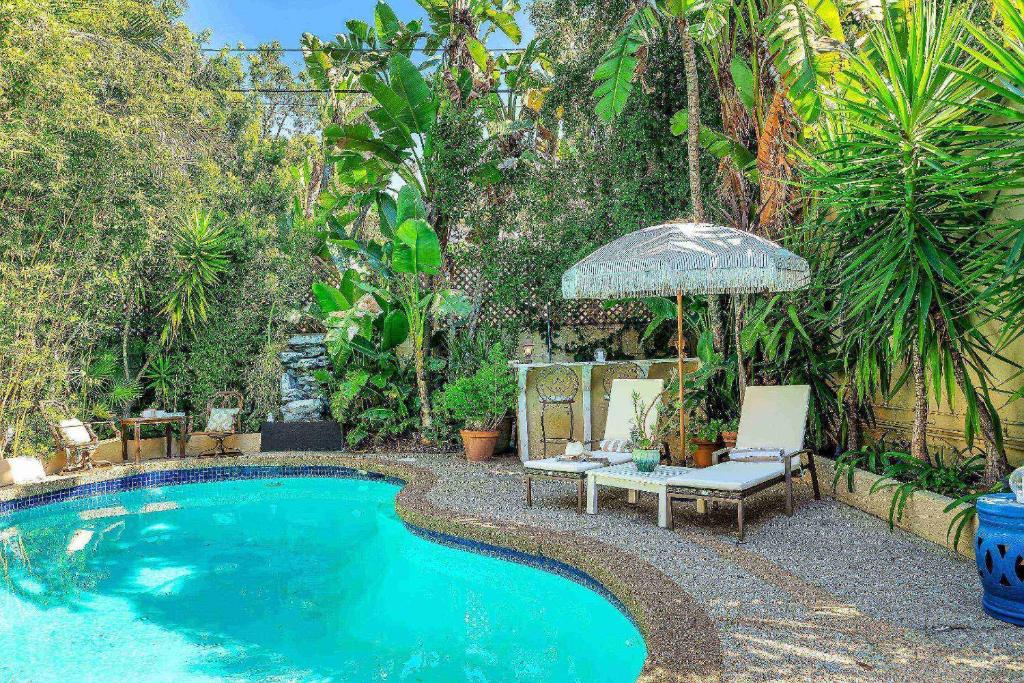 洛杉磯的住宿－Highland Haven Estate，一个带长凳和遮阳伞的游泳池