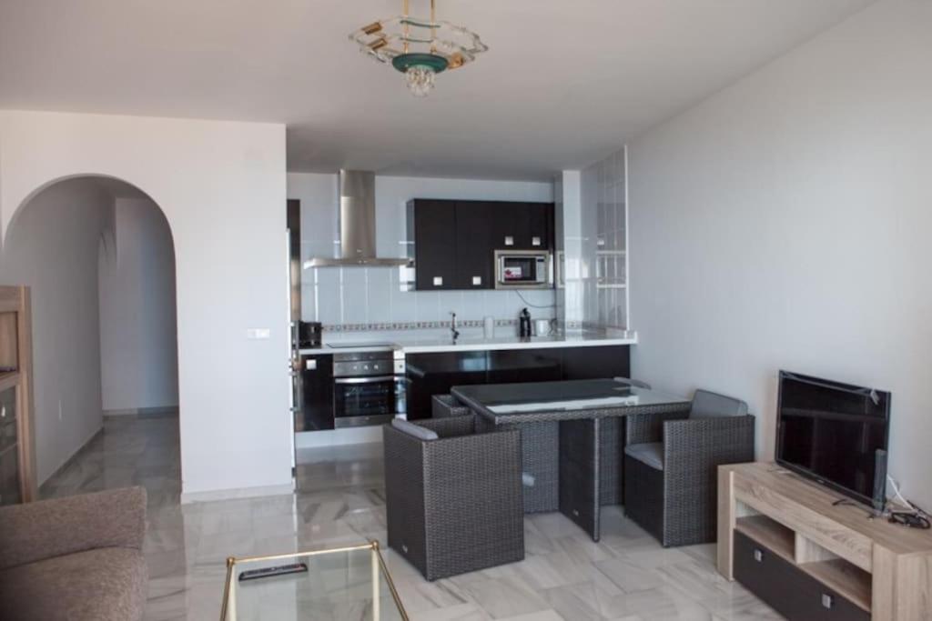 uma sala de estar com uma cozinha com uma mesa em Apartamento junto al mar en Torrox Costa em Málaga