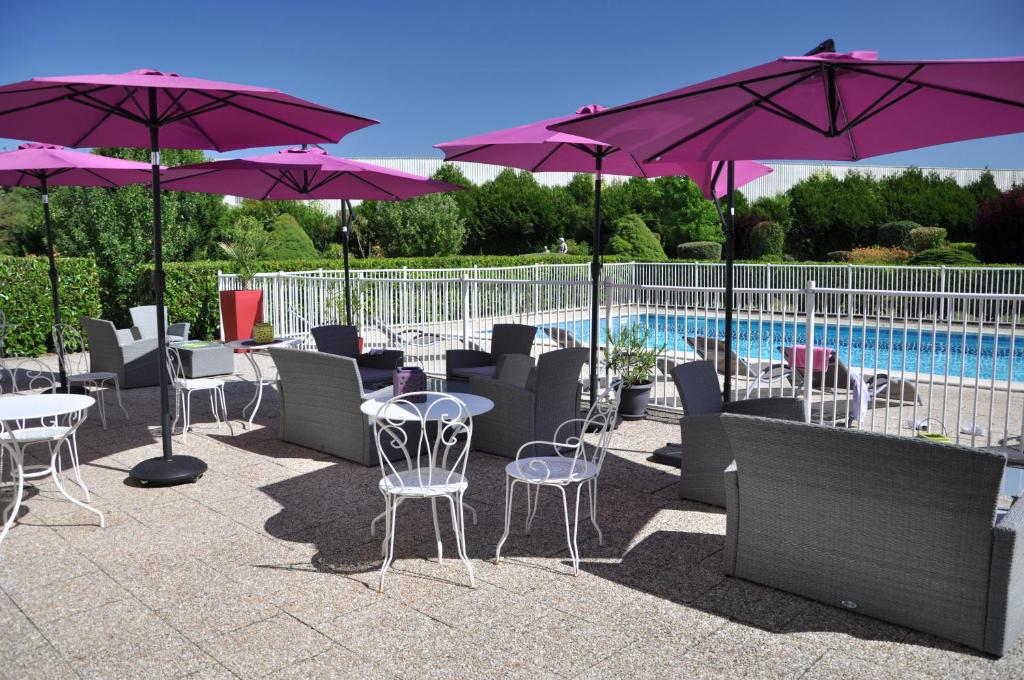 un patio avec des tables, des chaises et des parasols à côté d'une piscine dans l'établissement ibis Styles Gien, à Gien