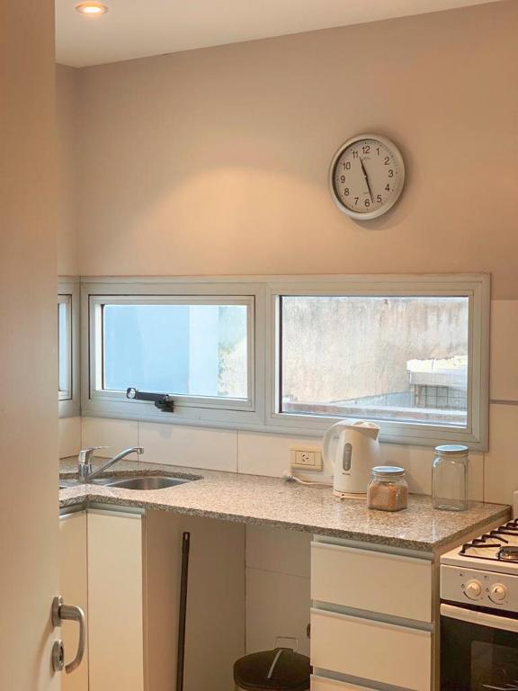 eine Küche mit zwei Fenstern und einer Uhr an der Wand in der Unterkunft Departamento céntrico y moderno in Río Cuarto