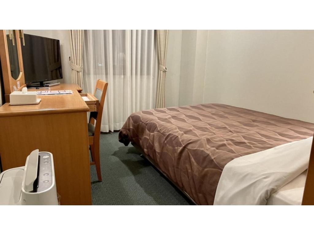 五所川原市にあるHotel Sunroute Patio Goshogawara - Vacation STAY 30370vのベッド、デスク、コンピュータが備わるホテルルームです。