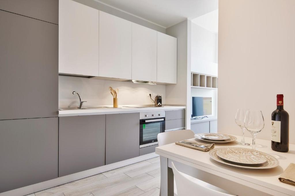 eine Küche mit weißen Schränken und einem Tisch mit Weingläsern in der Unterkunft Monviso Mono - Exclusive Apartment in Mailand