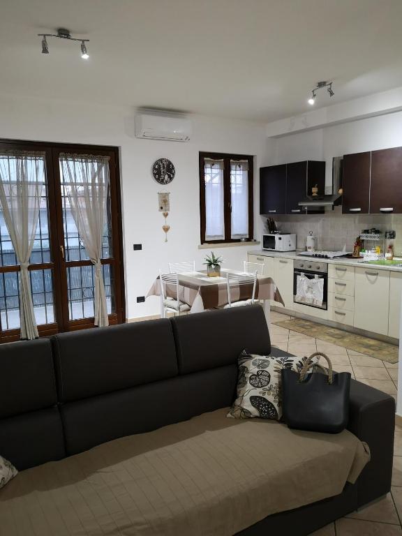 a living room with a couch and a kitchen at Sweet Home Airport Fiumicino in Fiumicino