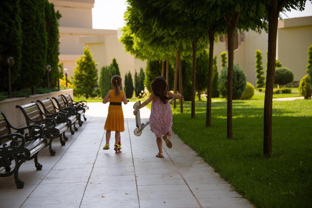 two little girls walking down a sidewalk in a park at Apart Hotel Apolonia Palace in Sinemorets