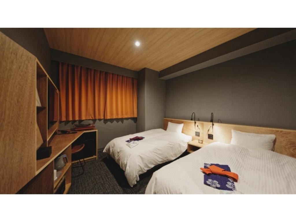 松山市にあるdogo hakuro - Vacation STAY 80200vのベッド2台とデスクが備わるホテルルームです。