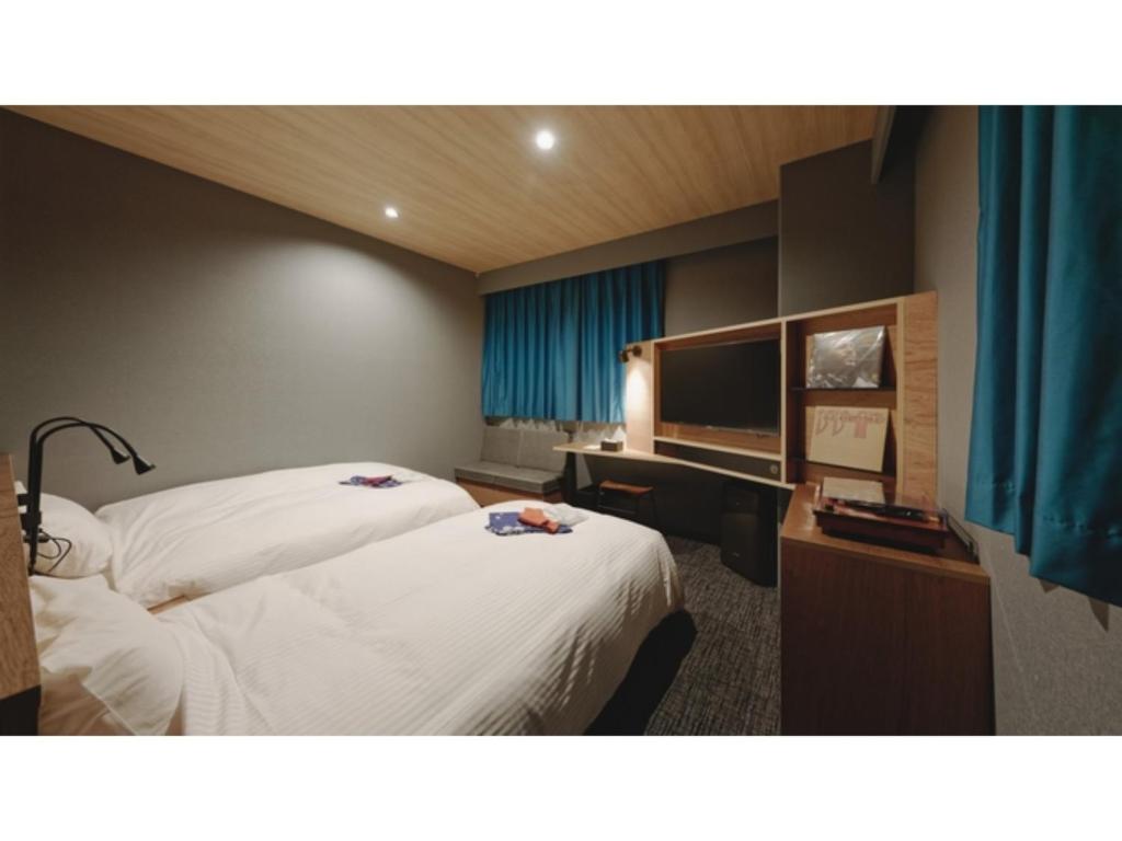 松山市にあるdogo hakuro - Vacation STAY 80207vのベッド2台とテレビが備わるホテルルームです。