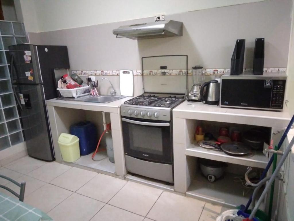 uma pequena cozinha com fogão e micro-ondas em WAYNA & WAYLLUY em Talara
