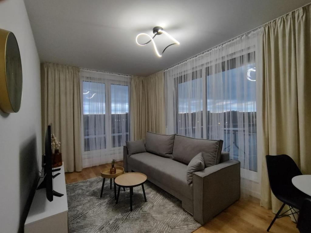 a living room with a couch and two large windows at ApartamentySnu, Bulwary II z parkingiem in Radom