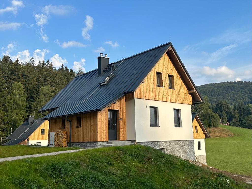 een huis met een zwart dak op een heuvel bij Chalupa 13ka - Horní apartmán in Smržovka