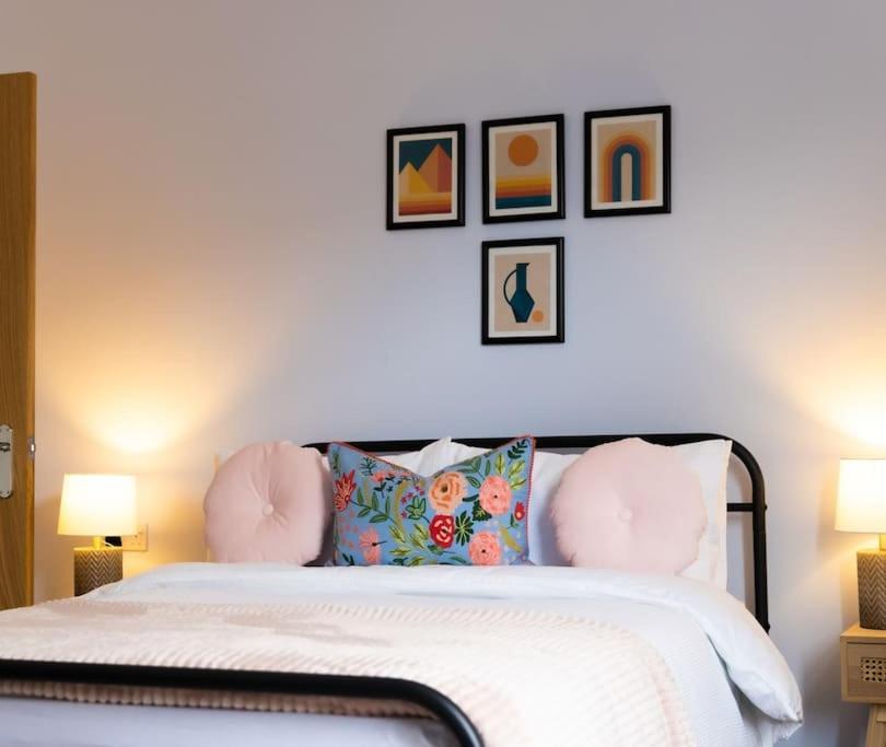 a bedroom with a bed with pillows and pictures on the wall at Cambridge Mews - Central Hebden Bridge in Hebden Bridge