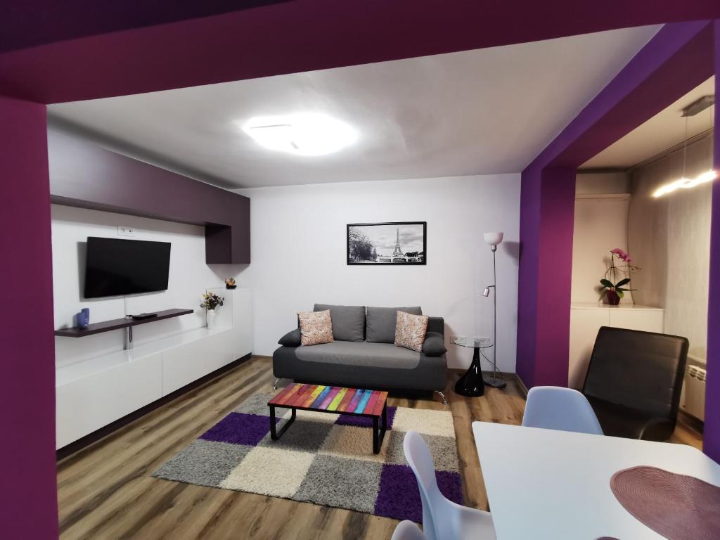 uma sala de estar com paredes roxas e um sofá em Apartament ASR em Piatra Neamţ