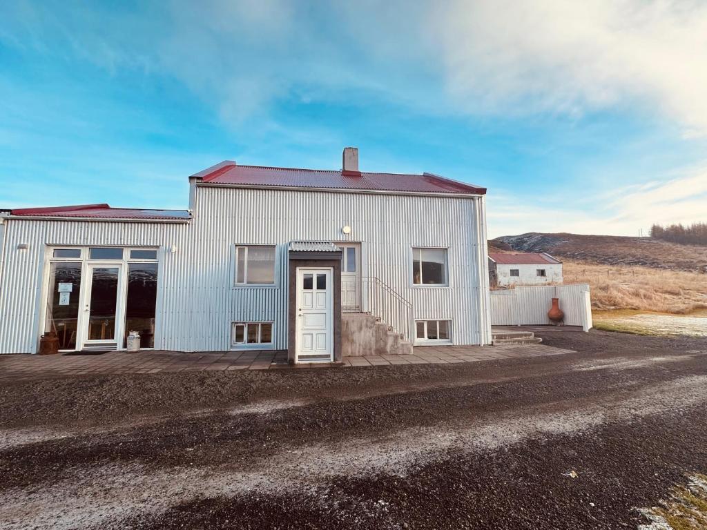 a white building with a door on a dirt road at Original North in Þingeyjarsveit