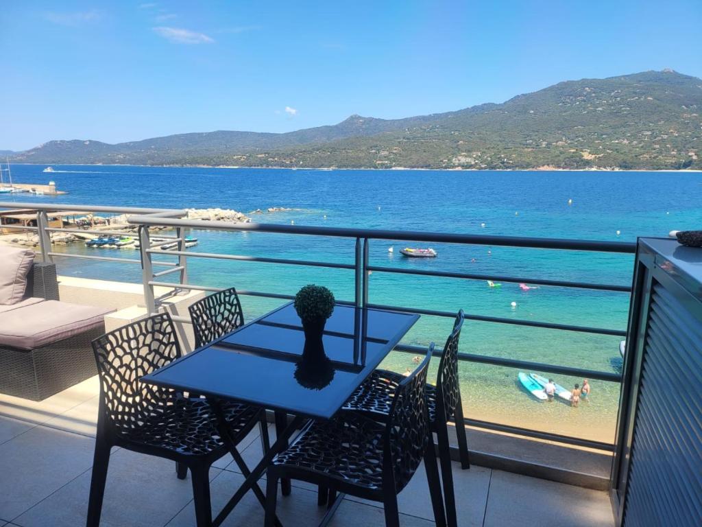 a table and chairs on a balcony with a view of the ocean at Appartement T2 terrasse vue mer à 180 in Propriano