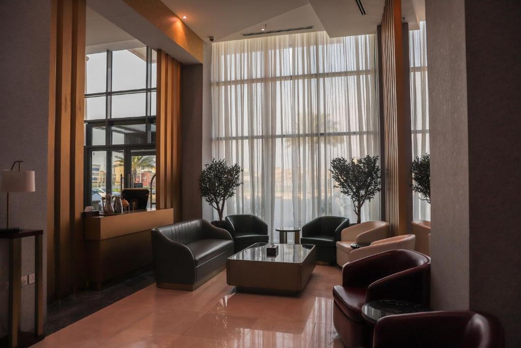 جراند أوتيل للشقق المخدومة Grand Otel Serviced Apartments في جازان: غرفة انتظار مع كراسي وطاولة ونوافذ كبيرة