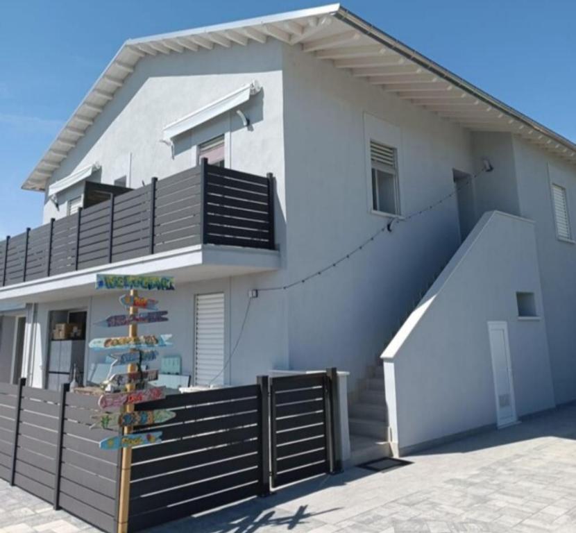 a white house with a balcony and a staircase at Appartamento Villa Matilde in Borgata Zarattini