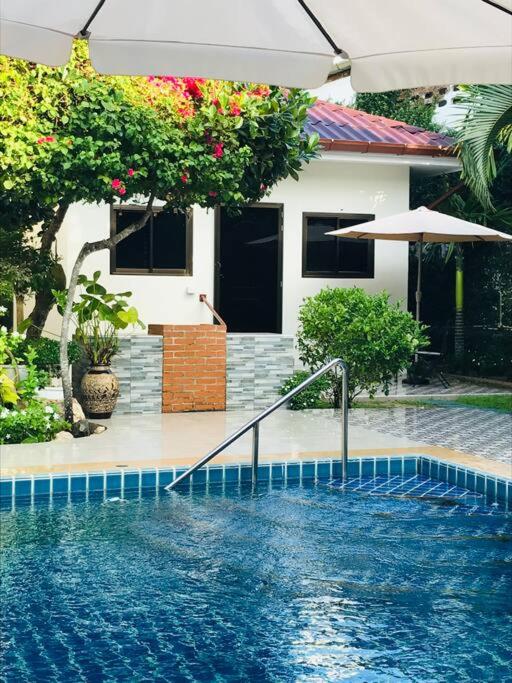 a swimming pool in front of a house at Summer House,shared pool, private bathroom and kitchen in Ban Phlu Yai
