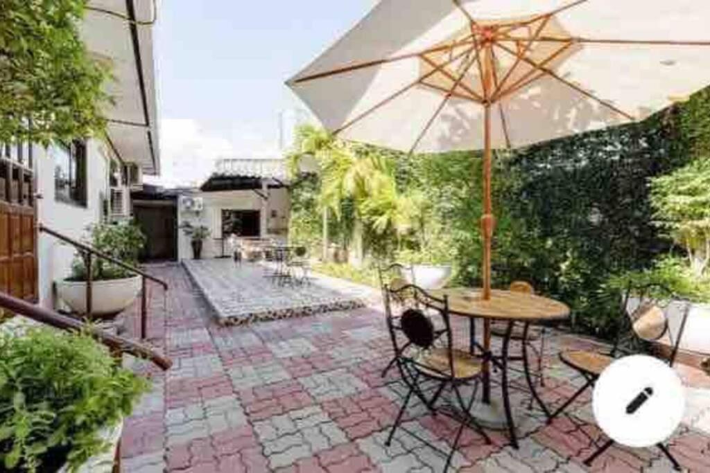 een patio met een tafel en een parasol bij Summer House,shared pool, private bathroom and kitchen in Ban Phlu Yai