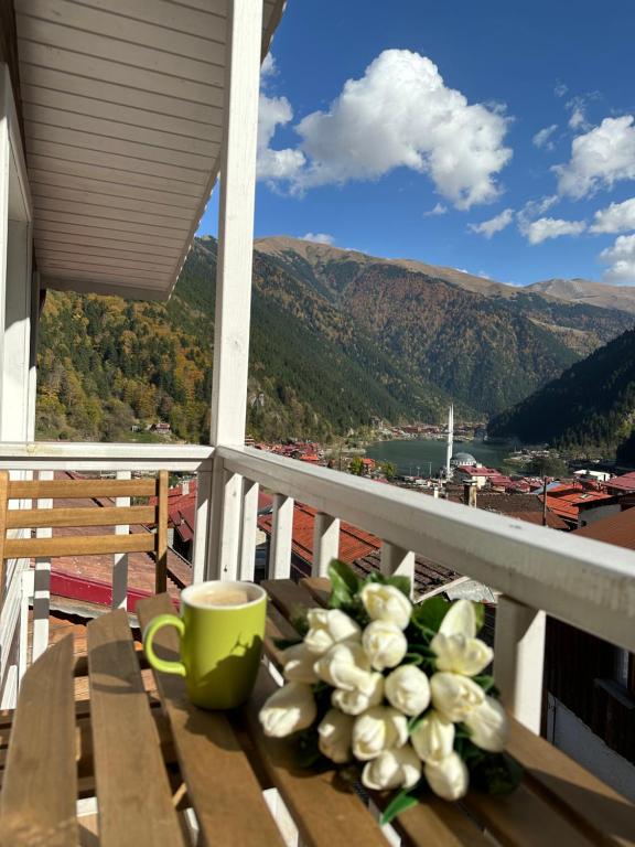 uma mesa com uma chávena e um vaso de flores numa varanda em Suit Rabando Uzungöl em Uzungol