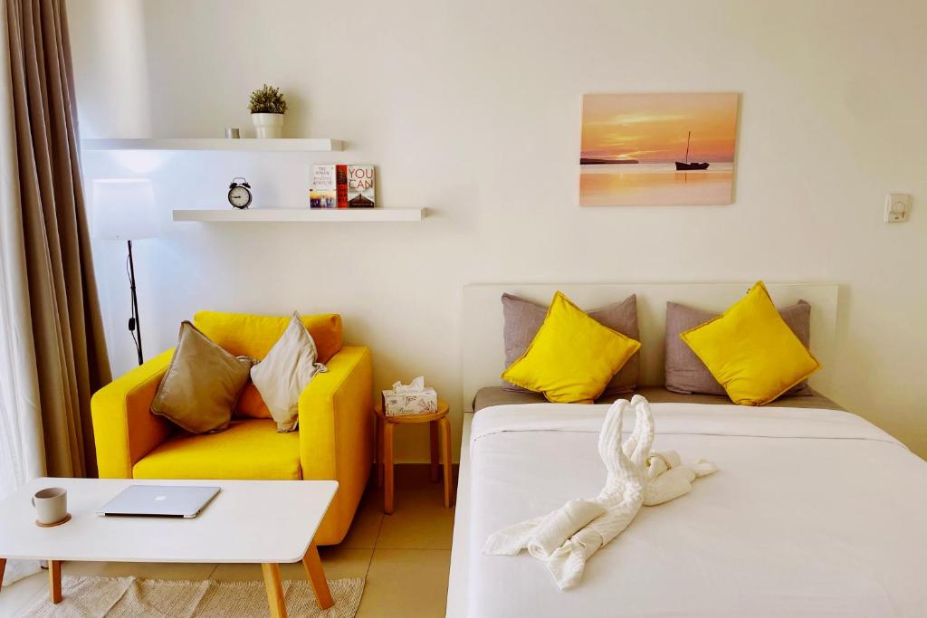 a bedroom with a bed and a yellow couch at Sunshine in Ras al Khaimah