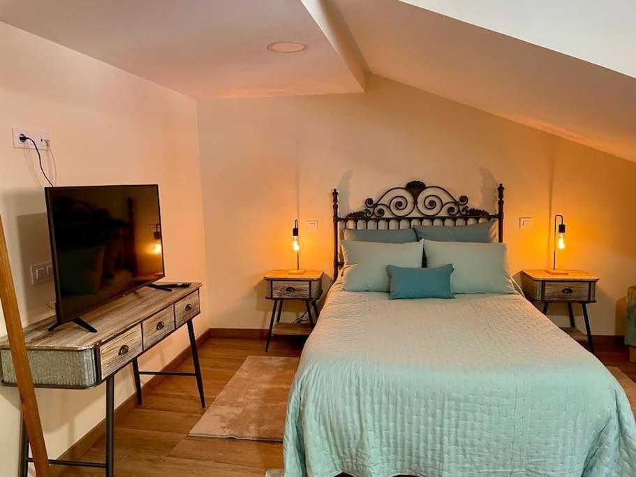 a bedroom with a large bed and a flat screen tv at Casina Marqués in Cudillero