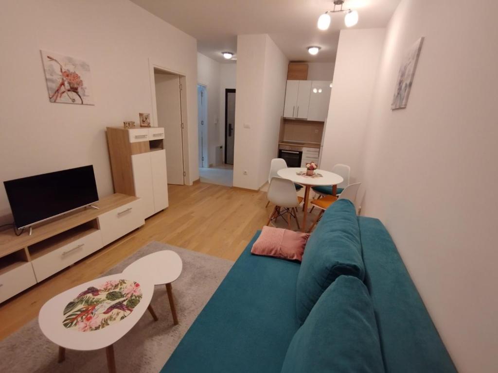ein Wohnzimmer mit einem blauen Sofa und einem Tisch in der Unterkunft Ada apartman in Banja Luka