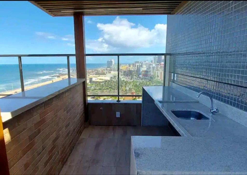 a bathroom with a sink and a view of the ocean at Vista mar no costa azul in Salvador