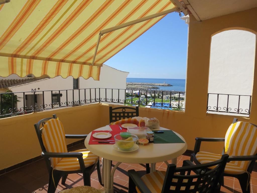 uma mesa e cadeiras numa varanda com vista para o oceano em Cabopino em Marbella