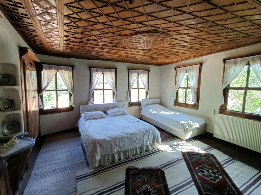 a bedroom with two beds in a room with windows at Hacı Şakirler Konağı in Mudurnu