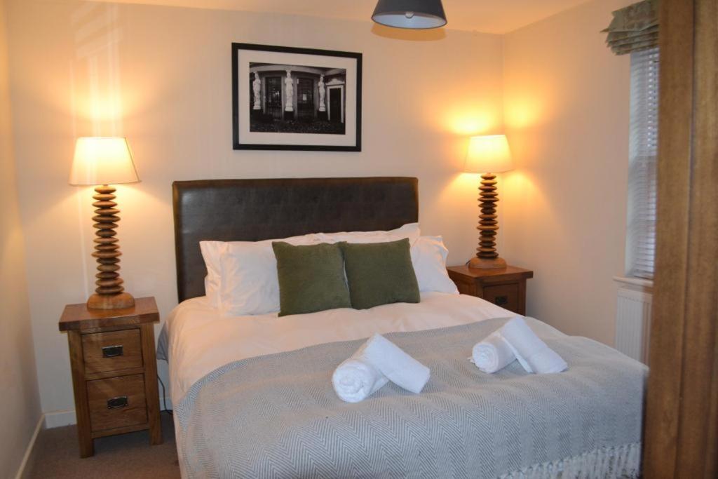 a bedroom with a large bed with two lamps at Entire apartments in the heart of the Suffolks - GL50 Apartments in Cheltenham