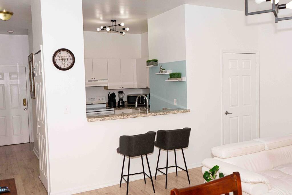 uma sala de estar com dois bancos pretos e uma cozinha em NEWLY Renovated condo 5 min from Airport em Miami