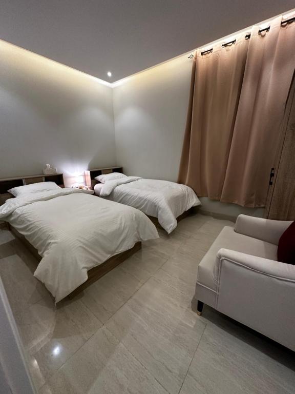 Hotel Apartment -7- L'Avner Al Moteab في الرياض: غرفة نوم بسريرين واريكة