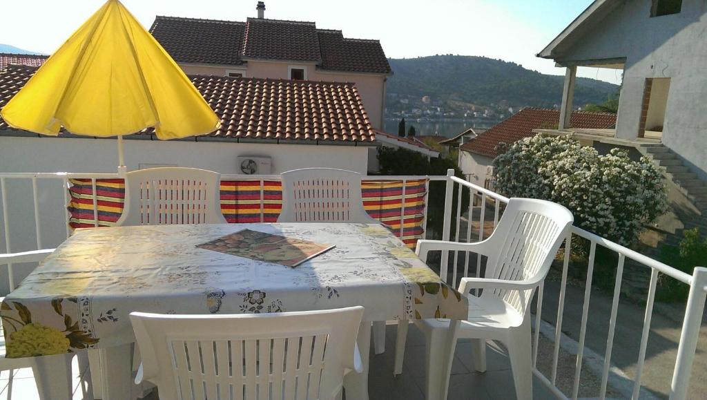 einen Tisch und Stühle auf einem Balkon mit gelbem Regenschirm in der Unterkunft Apartments Rogoznica in Rogoznica