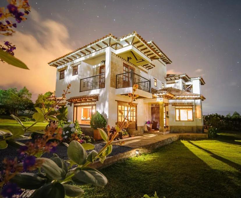 une grande maison blanche avec une pelouse devant elle dans l'établissement Casa de las Flores, à Villa de Leyva