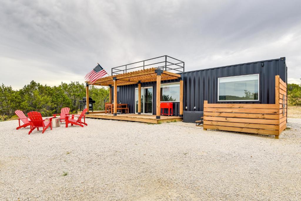 una casa negra con sillas rojas y una bandera americana en Remote Strawn Container Home with Hot Tub!, en Strawn