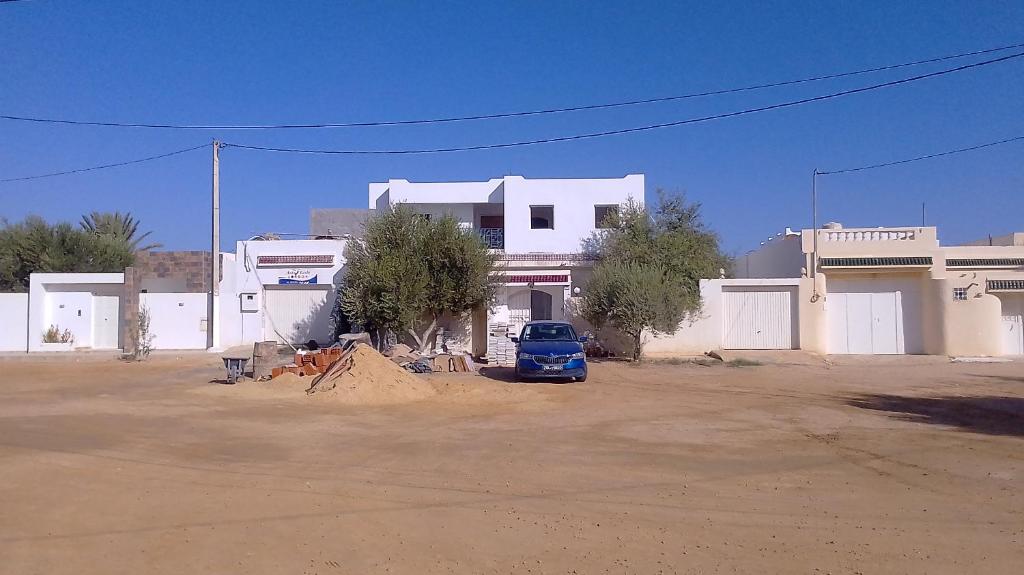 ein blaues Auto, das vor einem weißen Gebäude parkt in der Unterkunft JRAD in Houmt Souk