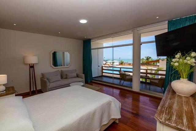1 dormitorio con 1 cama blanca grande y balcón en Hotel Boutique Caleta Grau, en Zorritos