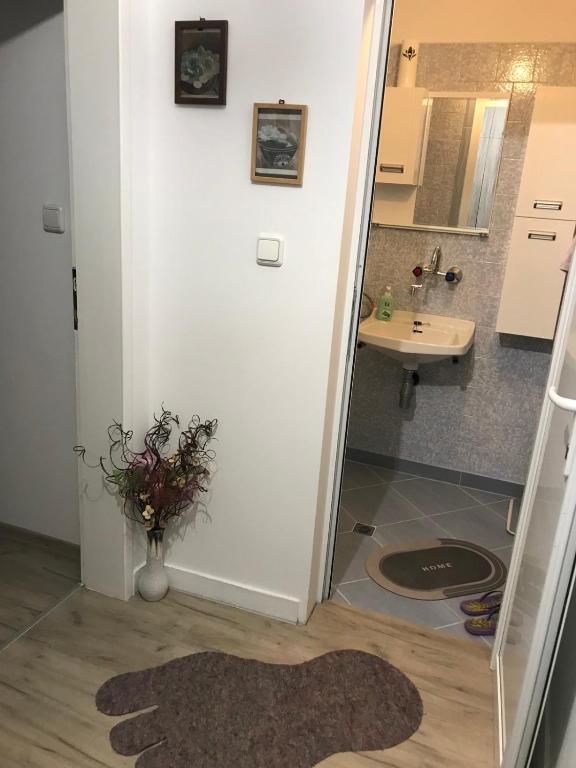 ein Badezimmer mit einem Waschbecken und einer Vase aus Blumen auf dem Boden in der Unterkunft Cozy loft apartment in Plewen