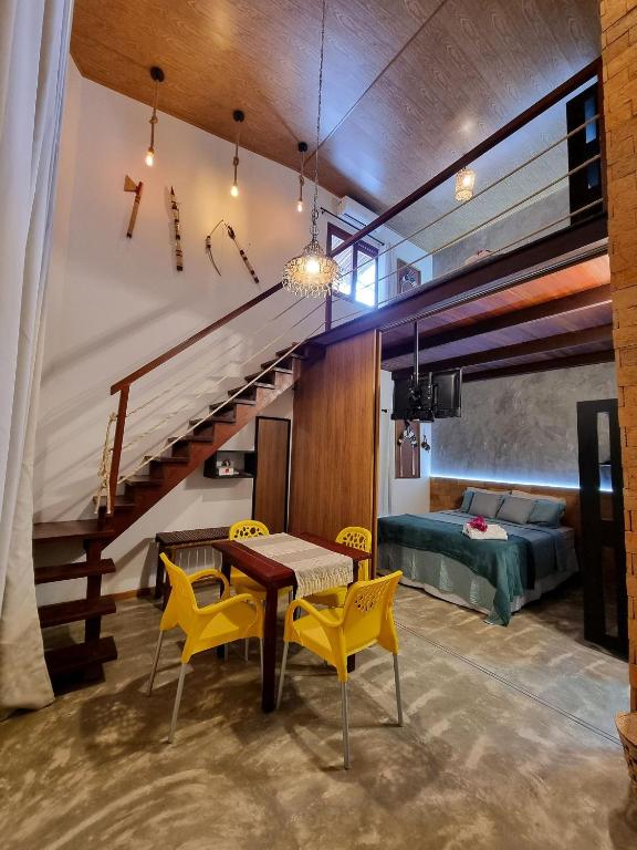 a room with a table and yellow chairs and a bed at Vila Manguezal, 2 suítes com opção de piscina e sauna integrada privativas na rota ecológica dos Milagres in Pôrto de Pedras