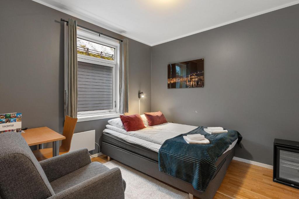 - une chambre avec un lit, une chaise et une fenêtre dans l'établissement Enter Backpack Hotel, à Tromsø