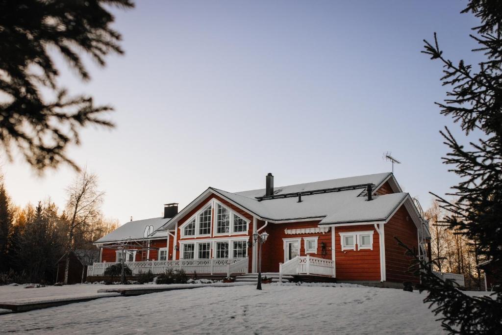 een groot rood huis met sneeuw op de grond bij Arcticmint in Rovaniemi