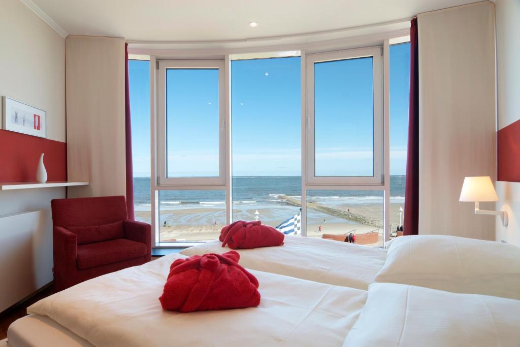 Schlafzimmer mit einem großen Bett und Strandblick in der Unterkunft Strandhotel Georgshöhe in Norderney