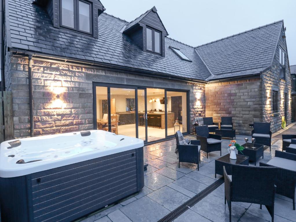 a hot tub on a patio with tables and chairs at Farley Meadow View in Matlock